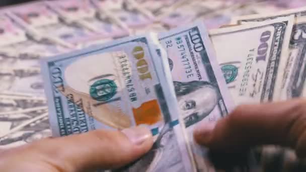 Mens handen houd een stapel van Amerikaanse Dollars tegen de achtergrond van roterende geld — Stockvideo