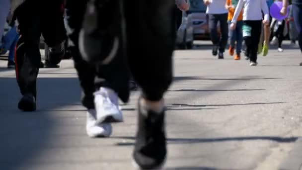 İnsanlar ve sporcular koşucular bacaklar kalabalık yolun şehrin git — Stok video