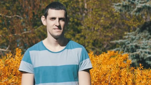 Retrato de un joven europeo guapo mirando con la lente y sonriendo en la naturaleza en el verano — Vídeos de Stock