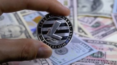 Ltc dolar faturaları bir zemin üzerine bir altın sikke Litecoin parmak elinde tutan