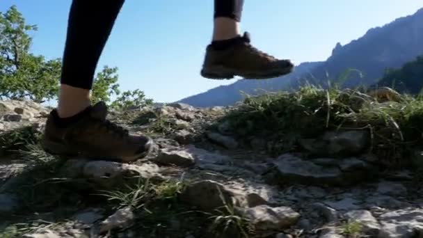 Blick auf die Füße einer Wanderin, die auf dem Gipfel der Klippe in den Bergen wandert. Zeitlupe — Stockvideo