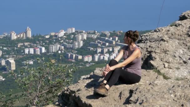 Mujer viajera se sienta en la cima de una montaña rocosa — Vídeo de stock