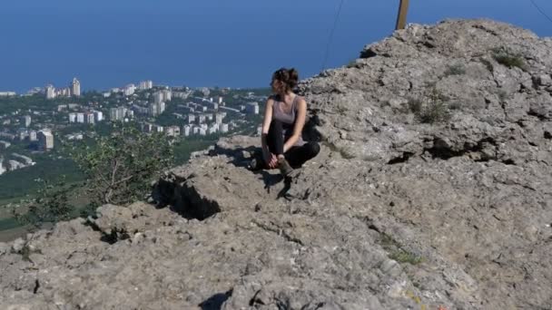 Mujer viajera se sienta en la cima de una montaña rocosa — Vídeos de Stock