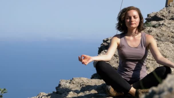 Γυναίκα ταξιδιώτη στοχάζεται σε βουνά, κάθεται στην κορυφή ενός βράχου στη θέση lotus — Αρχείο Βίντεο