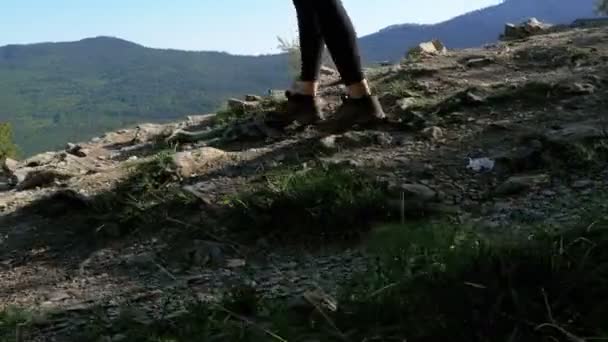 Blick auf die Füße der Wanderin, die auf der Spitze der Klippe in den Bergen wandert. Wandern auf Felsen — Stockvideo