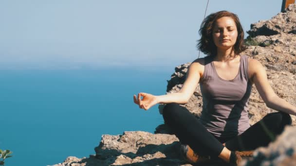 Hermosa joven practicando yoga y posiciones al aire libre en un increíble entorno de acantilado . — Vídeo de stock