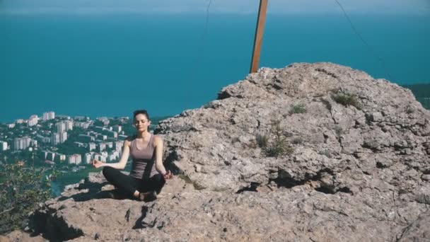 Hermosa joven practicando yoga y posiciones al aire libre en un increíble entorno de acantilado . — Vídeos de Stock
