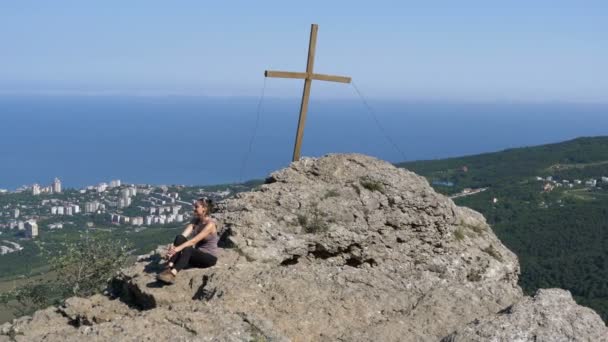 Mujer viajera se sienta en la cima de una montaña rocosa — Vídeos de Stock