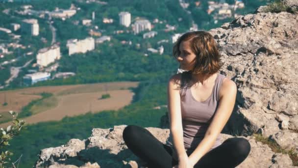 Mujer viajera se sienta en la cima de una montaña rocosa — Vídeo de stock
