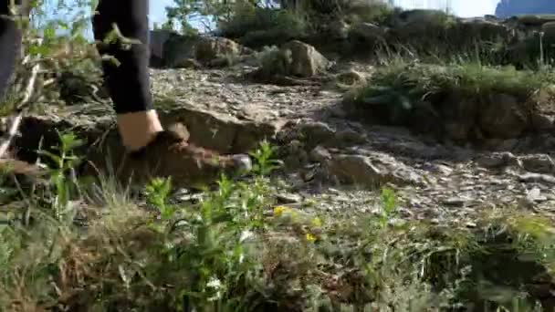Vista sui piedi del viaggiatore Donna Escursioni a piedi sulla cima della scogliera in montagna. Camminare sulle rocce — Video Stock