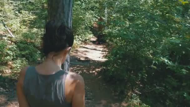 Вид сзади на прогулку женщины по лесной тропе в горах — стоковое видео