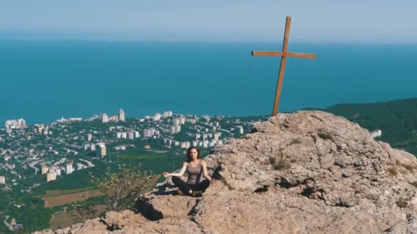 Vrouw reiziger mediteert in Bergen, zit op de top van een klif in de lotuspositie — Stockvideo