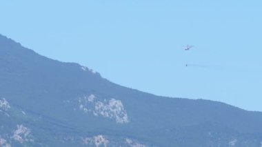 Bir yangın söndürmek için Dağların üzerinden uçan bir helikopter ile bir su deposu.