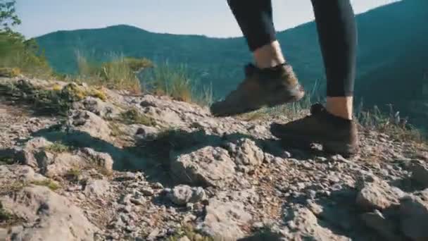 Ver en Pies de Mujer Viajera Senderismo Caminando en la cima del acantilado en la montaña. Caminando sobre rocas — Vídeos de Stock