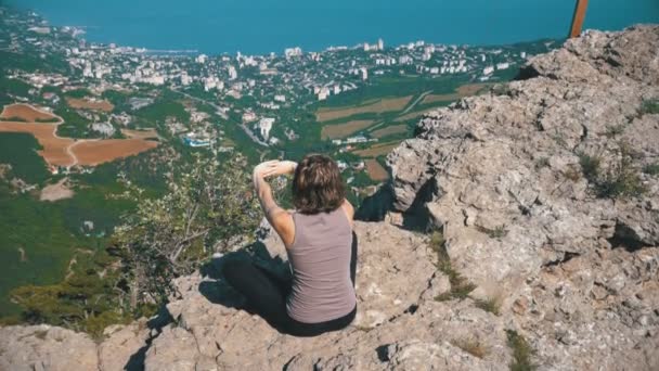 Sittande kvinna i lotusställning öva yoga flyttar eller mediterar och höjer armarna upp i bergen. — Stockvideo