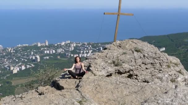 Vrouw reiziger mediteert in Bergen, zit op de top van een klif in de lotuspositie — Stockvideo