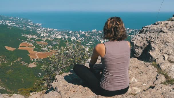 Donna seduta in posizione di loto praticare yoga si muove o medita e solleva le braccia in montagna . — Video Stock