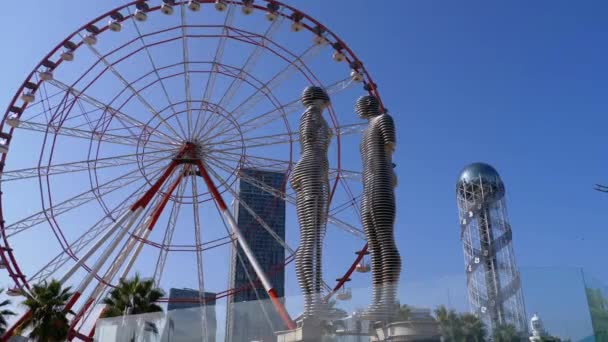 Grande Roue contre le ciel bleu avec statue d'Ali et Nino sur le remblai de Batoumi . — Video