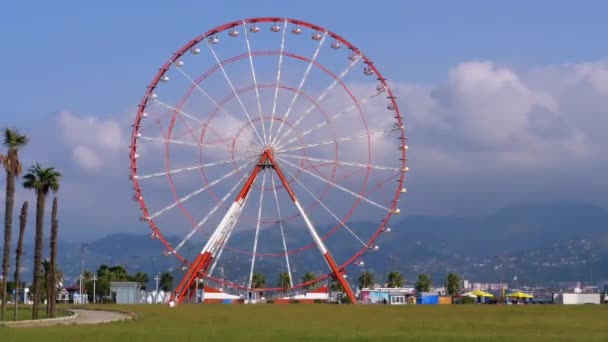 Riesenrad vor blauem Himmel mit Wolken in der Nähe der Palmen in der Kurstadt, sonniger Tag — Stockvideo