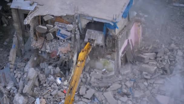 Zničení starého železobetonového domu pomocí mechanického ramene buldozeru na staveništi