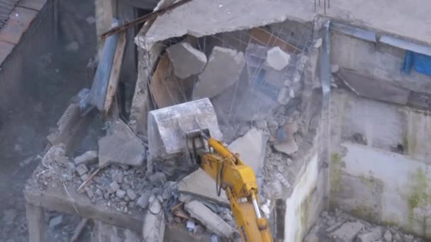 Destruindo a antiga casa de concreto usando braço mecânico de escavadeira no canteiro de obras — Vídeo de Stock