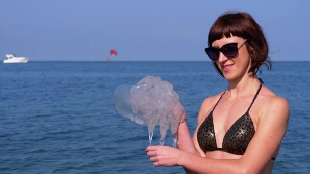 Frau hält eine große Seequalle vor dem Hintergrund des Schwarzen Meeres. Rhizostoma — Stockvideo