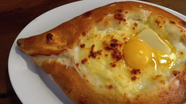 Adjarian Khachapuri on a Table in a Georgian Restaurant. Pastel de pan abierto con yema de huevo — Vídeo de stock