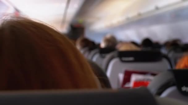 De salon van een passagiersvliegtuig met mensen die in stoelen zitten tijdens de vlucht. — Stockvideo