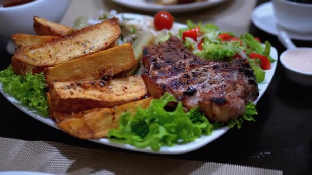 Biefstuk met aardappelen en salade op een tafel in een Georgisch restaurant — Stockvideo