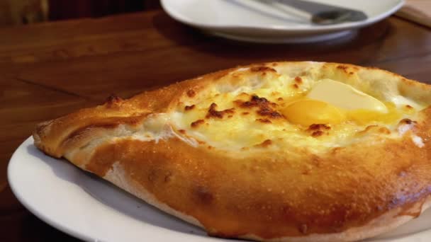 Adjarian Khachapuri em uma mesa em um restaurante georgiano. Torta de pão aberta com gema de ovo — Vídeo de Stock