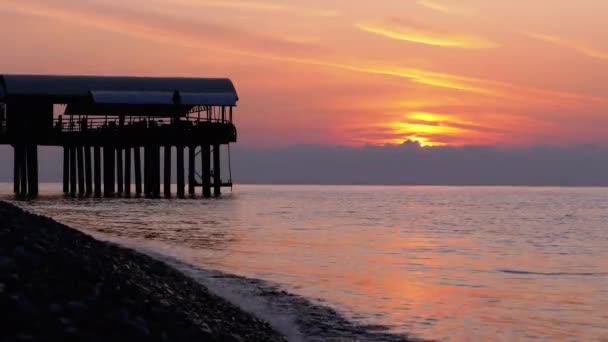 Panorama de la puesta de sol sobre el mar junto a la silueta del muelle . — Vídeos de Stock