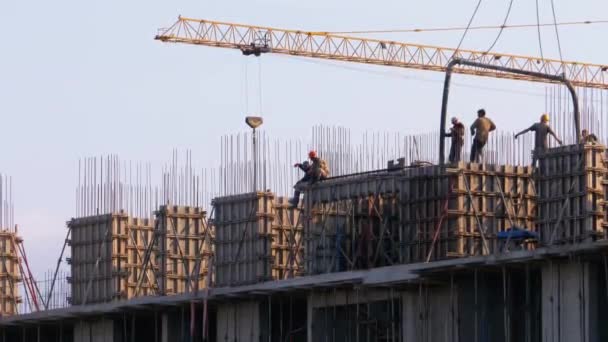 Werknemers op een bouwplaats. Een kraan op een bouwplaats tilt een lading op. — Stockvideo