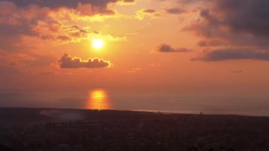 Deniz ve şehir üzerindeki bulutlarda gün batımı, hava manzarası..