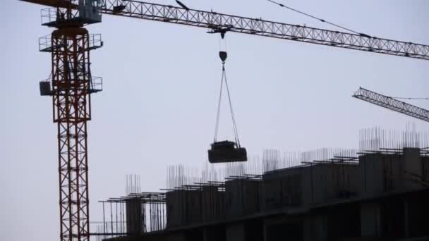 Věžový jeřáb na staveništi zvedá zatížení v budově. — Stock video
