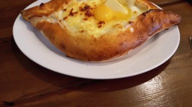 Adjarian Khachapuri Gürcistan Restoranında bir masada. Yumurta sarısı ile Ekmek Turtası Aç