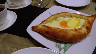 Adjarian Khachapuri Gürcistan Restoranında bir masada. Yumurta sarısı ile Ekmek Turtası Aç