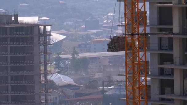 Тауэрский кран на строительной площадке поднимает груз в высотном здании . — стоковое видео