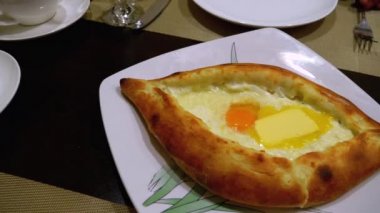 Adjarian Khachapuri Gürcistan Restoranında bir masada. Yumurta sarısı ile Ekmek Turtası Aç