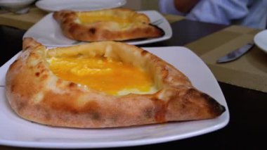 Adjarian Khachapuri Gürcistan Restoranında bir masada. Yumurta sarısı ile Ekmek Turtası Aç
