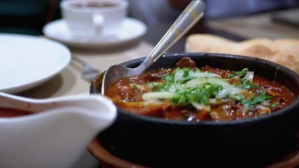 Georgian Meat Dish na Ketsi v restauraci. Chashushuli. Horké maso v hliněné pánvi na stole — Stock video