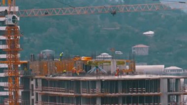 İnşaat alanındaki inşaatçılar. İnşaat alanındaki turna yükünü kaldırıyor. Yapı Yapımı.