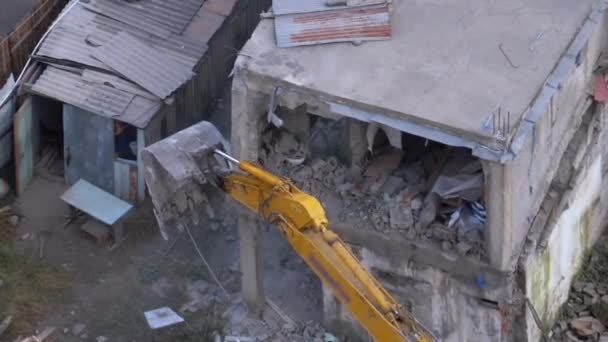 Destruyendo la vieja casa usando excavadora de cubo en el sitio de construcción . — Vídeo de stock