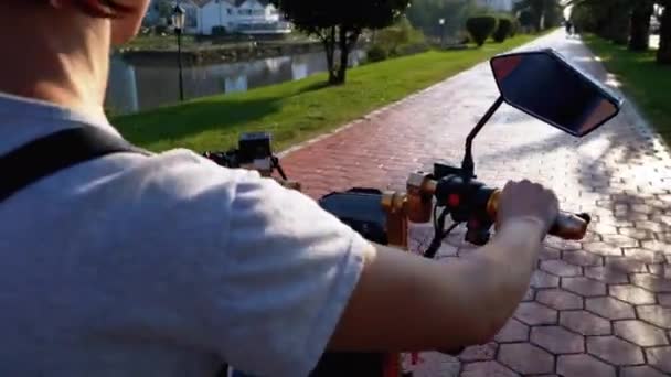 Vrouw rijdt een elektrische scooter op een rode fiets pad met palmbomen in het resort stad — Stockvideo