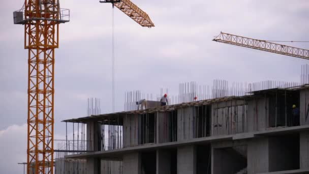 Constructores al borde de un rascacielos en construcción. Trabajadores en una obra de construcción . — Vídeo de stock