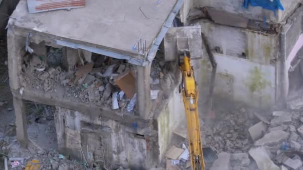 Destruyendo la antigua casa de hormigón usando el brazo mecánico de la excavadora en el sitio de construcción — Vídeo de stock