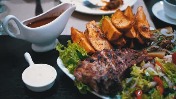 Biefstuk met aardappelen en salade op een tafel in een Georgisch restaurant — Stockvideo