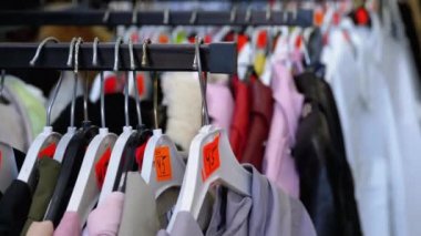 Giyim mağazası. Fiyat etiketli çeşitli elbiseler bir mağaza vitrininde asılı. Alıcılar Kıyafetleri Seçer