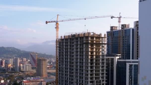 Construção civil. Um guindaste em um canteiro de obras levanta uma carga. Trabalhadores em um canteiro de obras — Vídeo de Stock