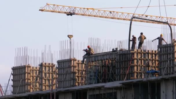 Byggare på en byggarbetsplats. Kran på en byggarbetsplats lyfter en last. Byggnadskonstruktion. — Stockvideo