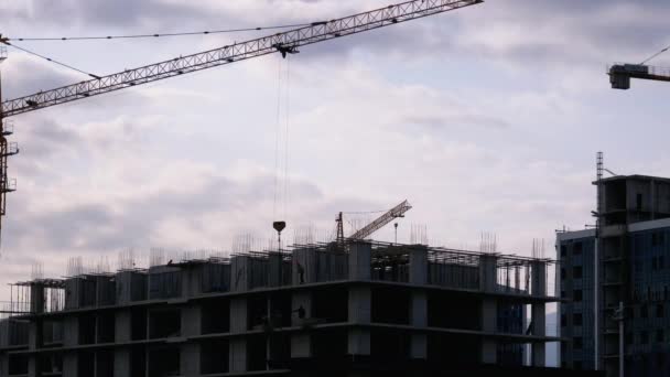 Construcción de edificios. Una grúa en un sitio de construcción levanta una carga . — Vídeos de Stock